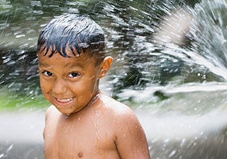 Child playing in sprinkler